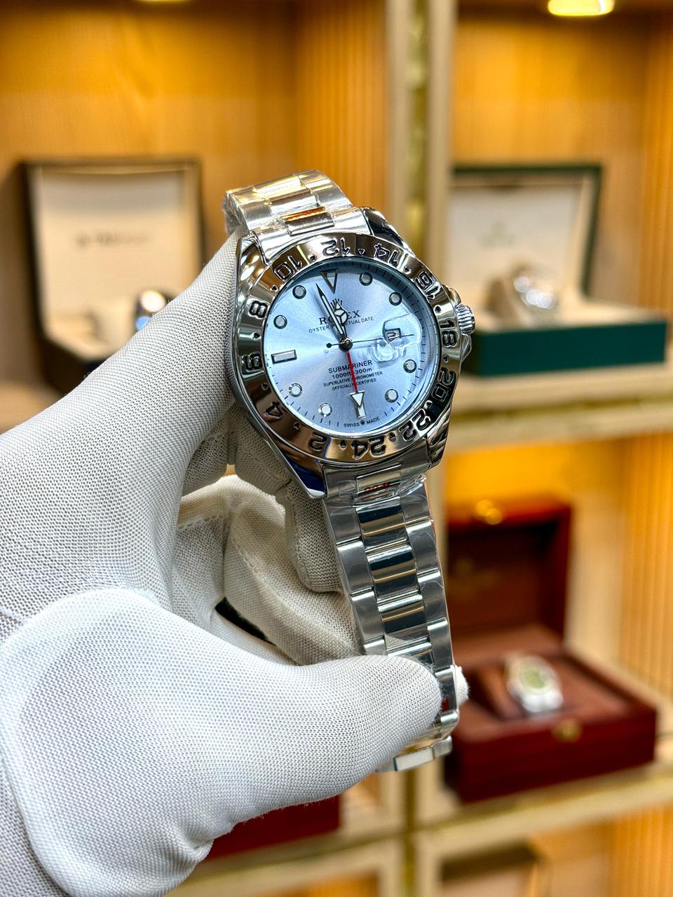 Silver watch held by a gloved hand with a blurred background