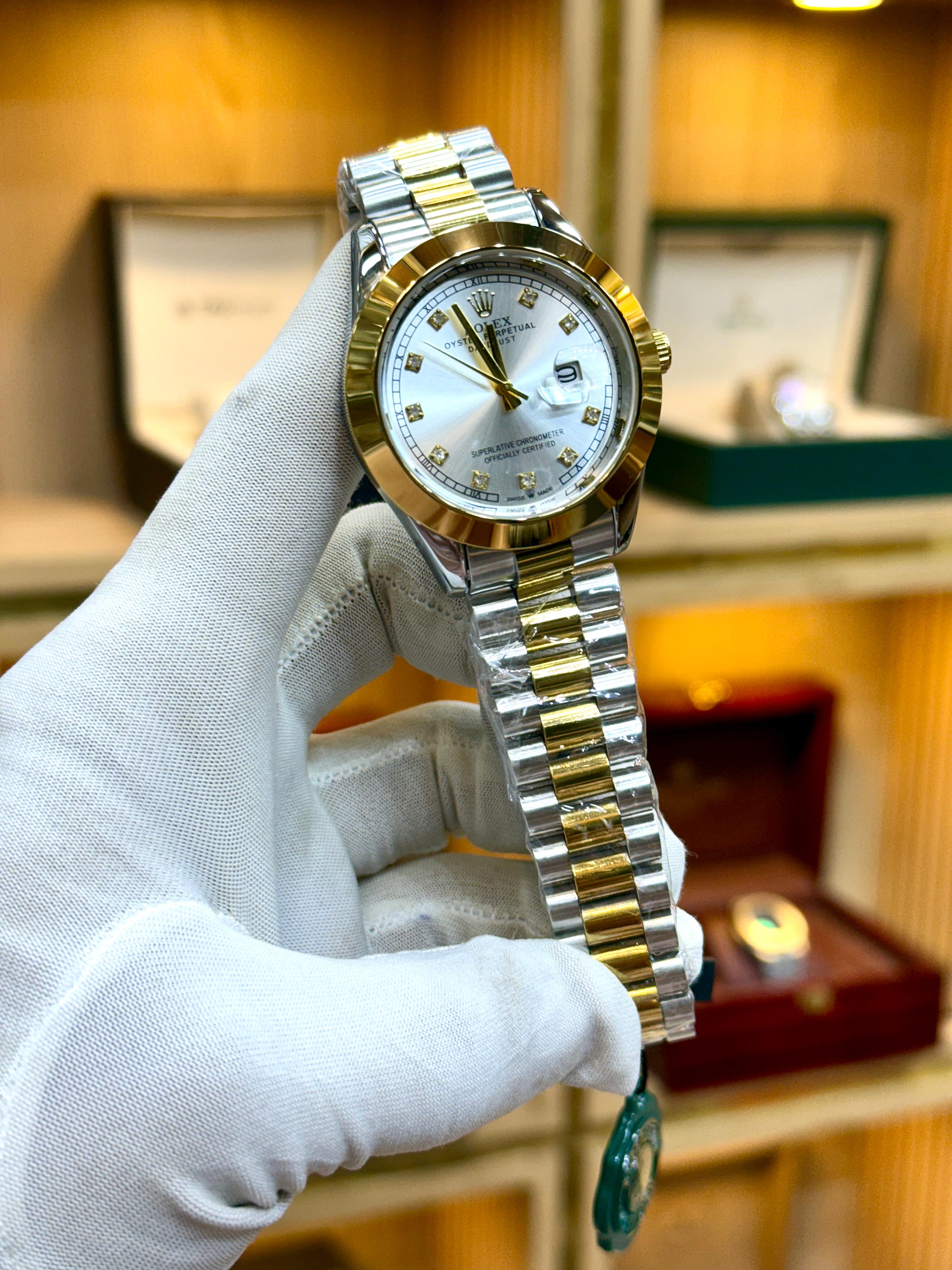 Gold and silver watch held by a gloved hand with a blurred background