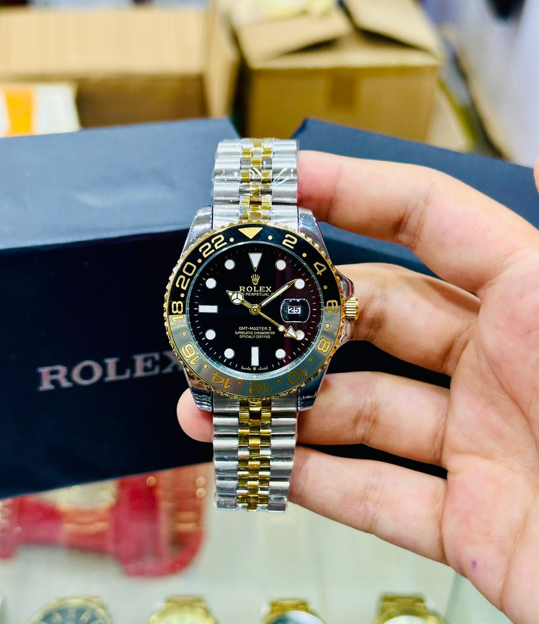 Hand holding a two-tone Rolex watch with a black face against a blurred background.