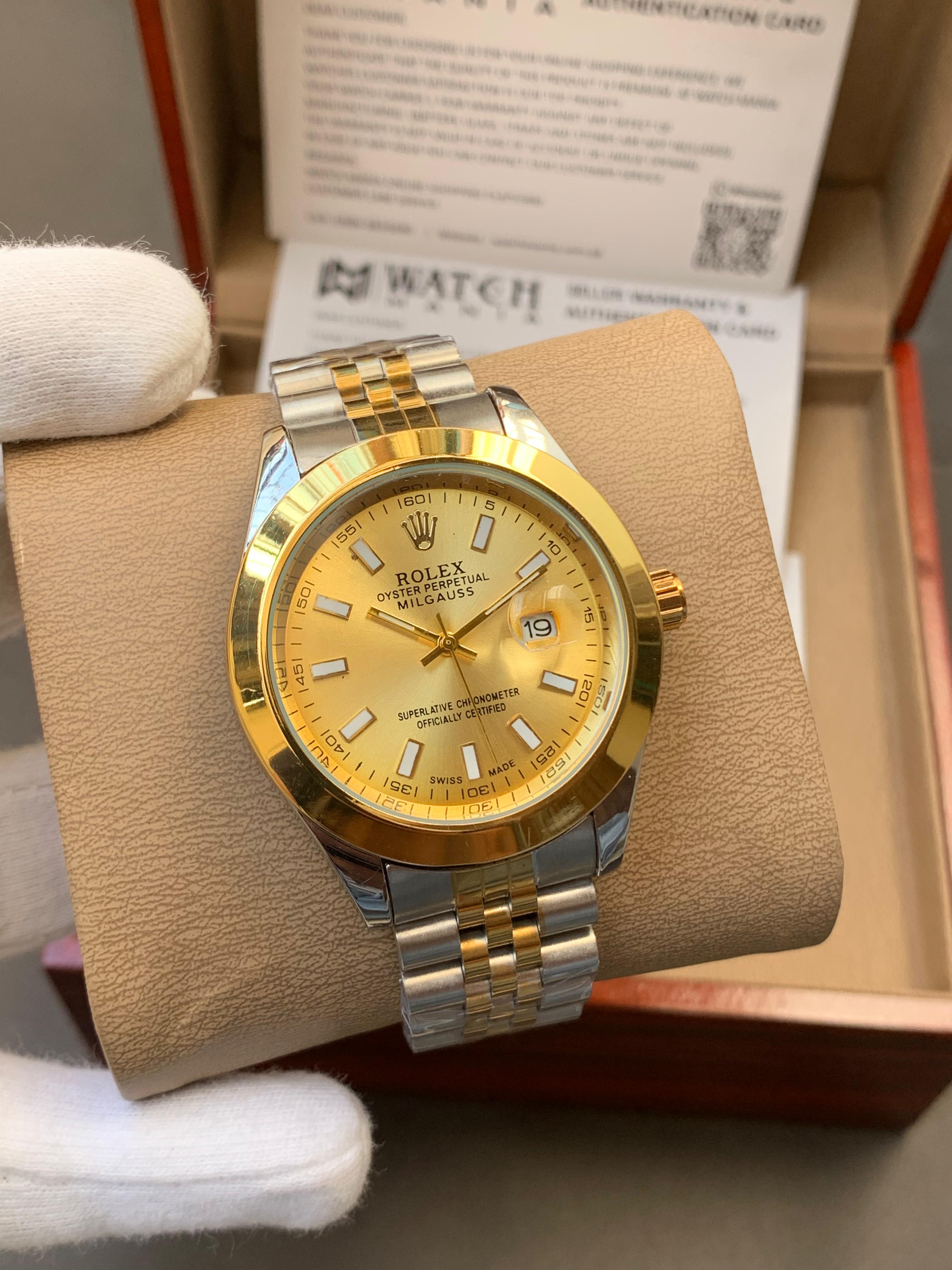 Gold and silver watch on gold display with a box and paper in the background