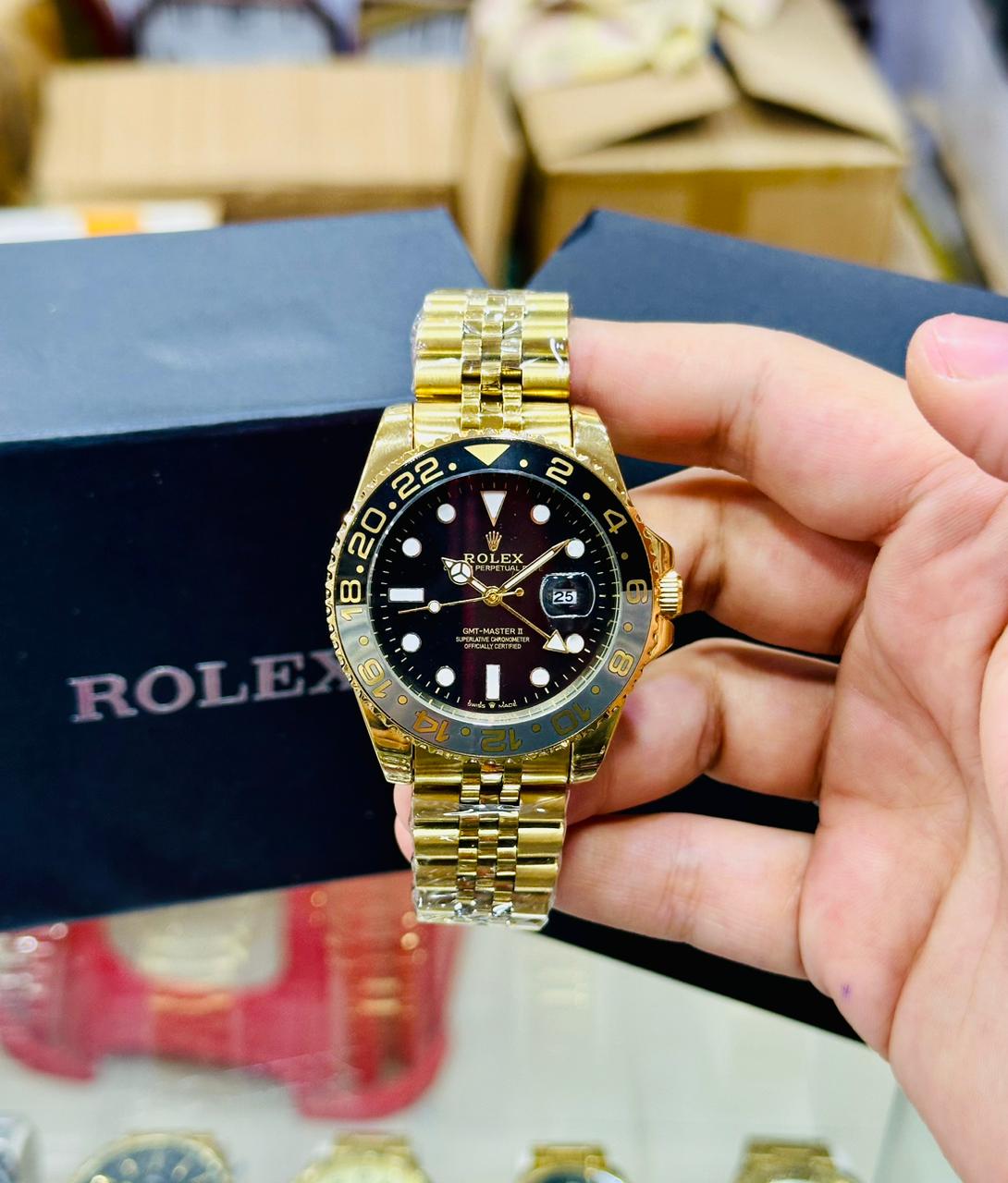 Gold Rolex watch held by a hand with a blurred background