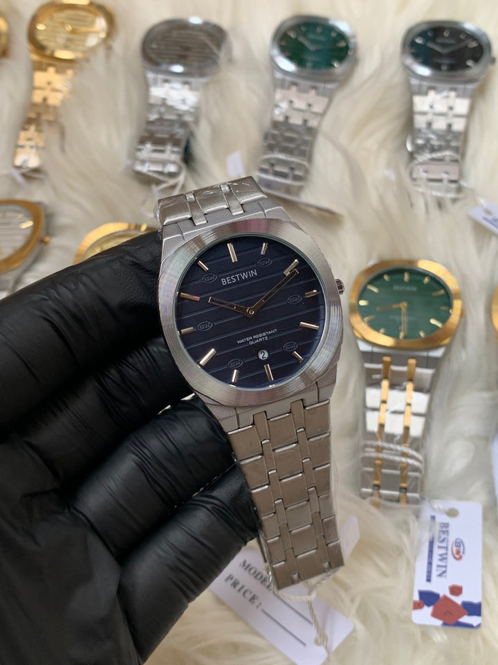 Silver watch held by a gloved hand with other watches in the background