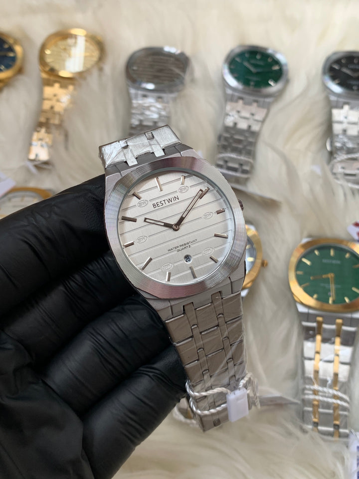 Silver watch held by a gloved hand with other watches in the background